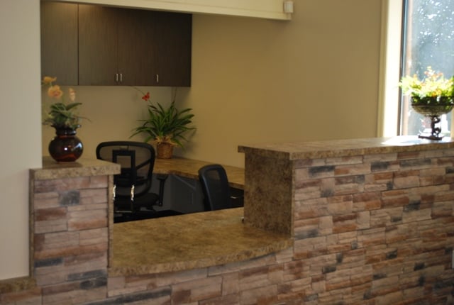 Reception counter featuring a stacked stone facade and brown granite countertop.