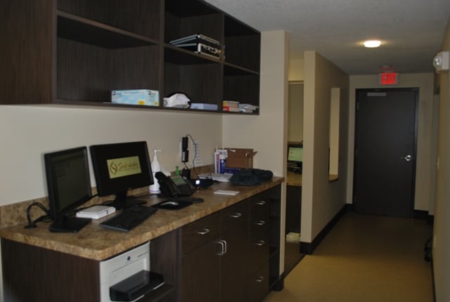 Computer workstation with dual monitors and dark wood cabinetry located in a hallway.