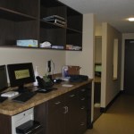 Computer workstation with dual monitors and dark wood cabinetry located in a hallway.