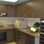 Professional sterilization room with wood cabinets, stone counters, and a benchtop autoclave.