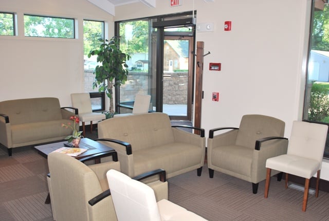 Bright office lobby featuring neutral-toned sofas, chairs, and large windows looking outside.
