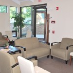 Bright office lobby featuring neutral-toned sofas, chairs, and large windows looking outside.